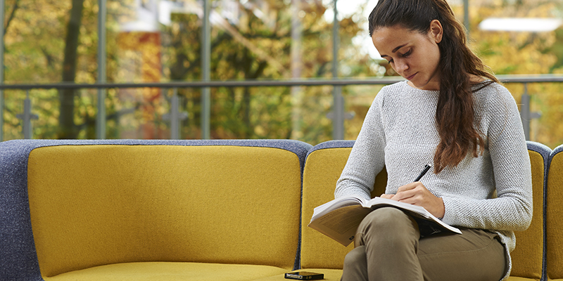 Female student studies alone on a sofa