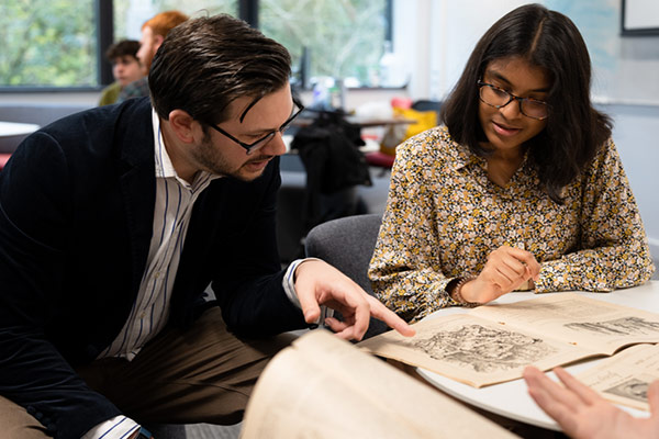 A student and teacher discussing a historical manuscript